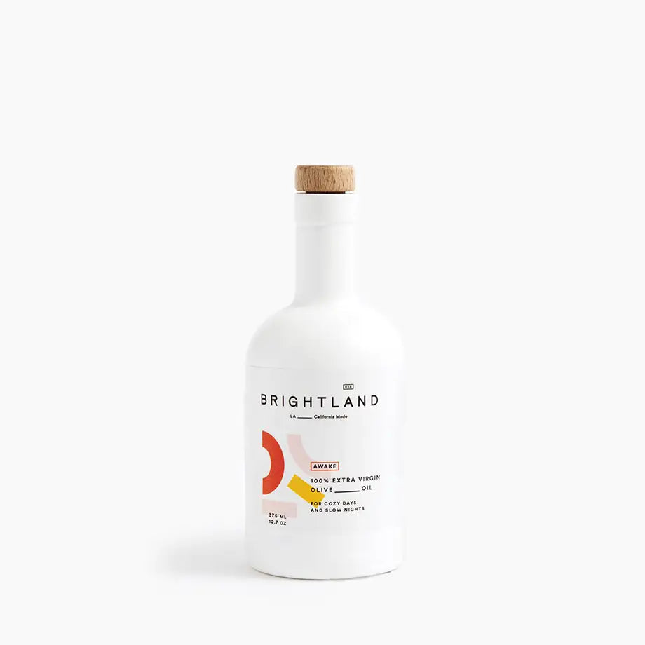 Brightland Awake 100% Extra Virgin Olive Oil in a white bottle with a wooden cap, featuring a modern label design.