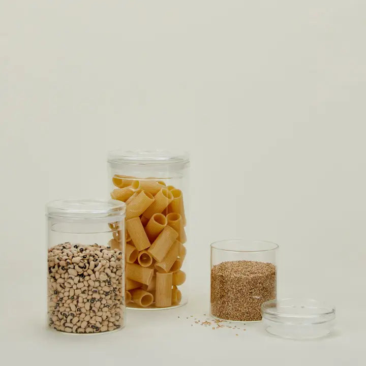Hawkins New York Essential Glass Storage Containers filled with pasta, grains, and beans, showcasing their minimalist, functional design with clear glass and matching lids. Perfect for pantry organization and stylish kitchen storage.